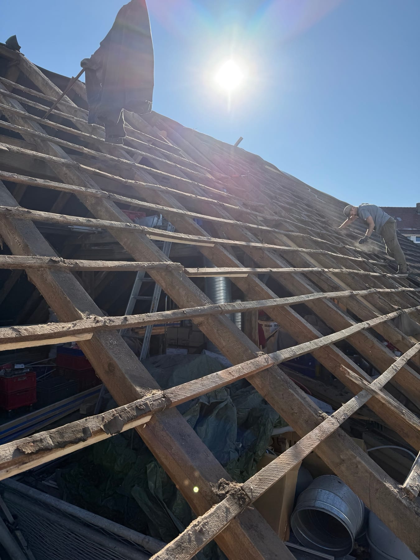 Die freigelegte alte Dachlattung des Capitol im Gegenlicht, ein Handwerker arbeitet am oberen Rand